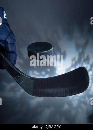 Helsinki / Finlande - 4 JUIN 2022 : gros plan d'un bâton de hockey sur glace noir qui tisse un palet sur fond de rêve. Banque D'Images