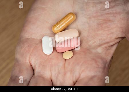 Femme âgée main tenant cinq pilules ou médicaments différents Banque D'Images