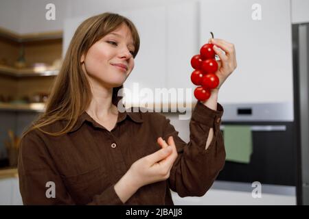 Femme regardant la branche de tomate de cerise dans sa main Banque D'Images