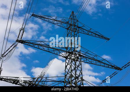 Réseau électrique de poteaux sur un panorama de ciel bleu et de prairie verte. Banque D'Images