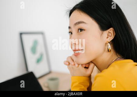 Jeune femme asiatique attentionnés qui ne pense pas à son bureau Banque D'Images