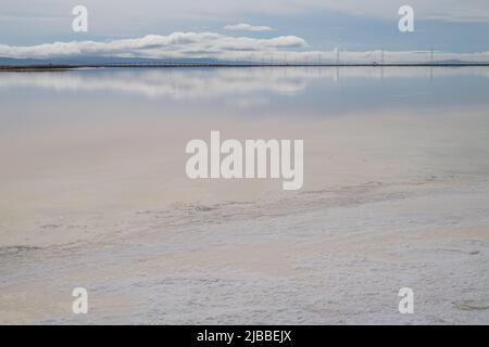 L'eau vitreux de type miroir des étangs d'évaporation de sel reflétant les nuages et les lignes électriques. Banque D'Images