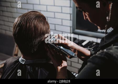 Homme qui obtient une coupe de cheveux tendance au salon de coiffure. Banque D'Images