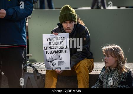 Homme avec beanie tenant une affiche à Ylikulutuskapina démonstration par extinction Rebellion Finlande ou Elokapina à Mannerheimintie, Helsinki, Finlande Banque D'Images