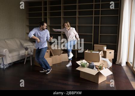 Couple gaie fêtez la danse du réchauffement de la maison dans le salon non meublé Banque D'Images