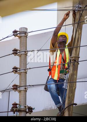 Dar es Salaam, Tanzanie - février 2021 : homme africain qui fait de l'électricité sur un poteau électrique. Afrique. Banque D'Images