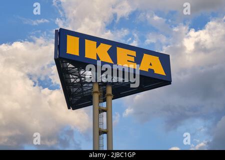 Signe du logo IKEA sur un grand poteau, avec des nuages du soir. IKEA est un conglomérat multinational suédois qui conçoit et vend des meubles prêts à assembler Banque D'Images