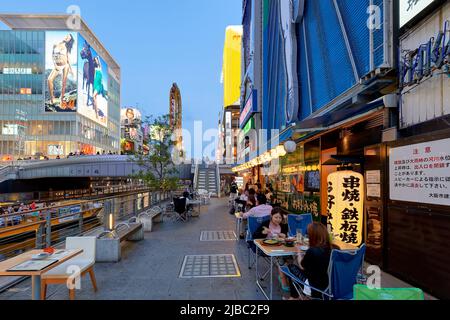 Japon. Kansai. Osaka. Panneaux lumineux dans le district de Dotonbori au coucher du soleil. Manger dehors le long du canal Banque D'Images