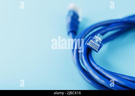 Bobine d'un câble réseau Internet pour la transmission de données sur fond bleu. Cordon de raccordement pour câble LAN. Banque D'Images
