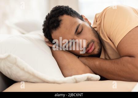 Arabe Homme se tenant les mains derrière la tête dormant dans la chambre Banque D'Images