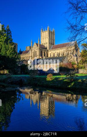 Cathédrale de Wells avec un reflet presque parfait sous le soleil d'hiver dans une piscine du Bishop's Palace, Somerset, Angleterre, Royaume-Uni Banque D'Images