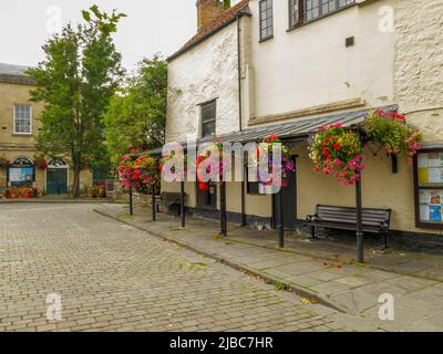 Une exposition colorée de paniers suspendus dans le marché pavé à Wells, Somerset, Angleterre, Royaume-Uni Banque D'Images