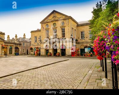 Une exposition colorée de paniers suspendus et de l'hôtel de ville dans la place pavée du marché à Wells, Somerset, Angleterre, Royaume-Uni Banque D'Images