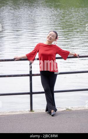 Une femme asiatique élégante et gracieuse qui aime danser pose pour des photos près d'un lac dans un parc à Queens, New York. Banque D'Images