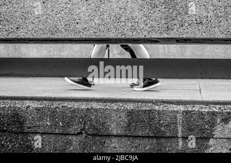 Pieds et jambes marcher le long d'une passerelle de style brutaliste à Londres Southbank - Queen Elizabeth Hall. Banque D'Images