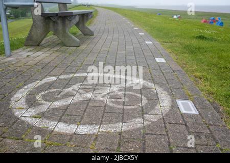 Sentier en pierre avec un panneau interdisant le vélo peint dessus, sur le fond d'un banc. Concept de sécurité. Banque D'Images