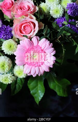 un beau bouquet de fleurs avec des roses roses roses et un gerbera rose clair sur fond sombre, espace de copie, vue d'en haut Banque D'Images