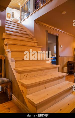 Escalier en bois de pin verni clair dans la salle du sous-sol à l'intérieur de la réplique de l'ancienne maison en pierre de champ régime français de 1700s. Banque D'Images