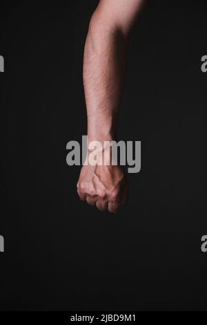 Main brutale de mans avec nervures saillantes, fond noir Banque D'Images