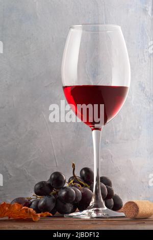 Un verre de vin rouge avec du raisin et du liège sur une table en bois. Gros plan Banque D'Images