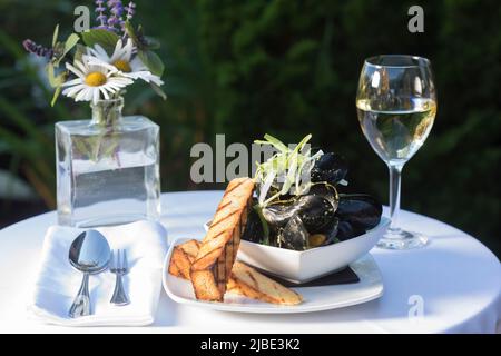 Un plat de moules avec vin dans un cadre extérieur Banque D'Images