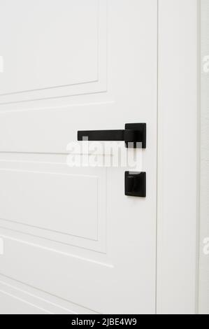 poignées de porte noires sur une porte en bois blanc, gros plan d'une partie de l'intérieur Banque D'Images