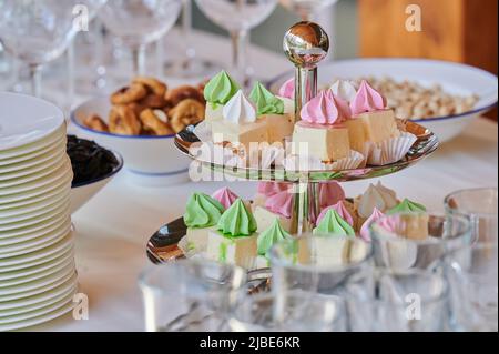 gâteaux meringue sur un plateau à deux niveaux avec plats sur une table lors d'une fête pour recevoir les invités lors d'un événement dans un restaurant Banque D'Images