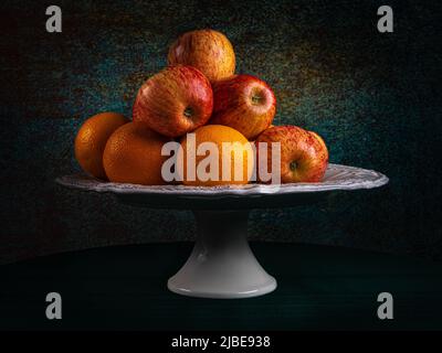 Assiette de fruits, pommes et oranges. Dans une photo de moody, une image d'une vie encore, des pommes et des oranges fraîches. Suggestion d'utilisation sur un canevas. Banque D'Images