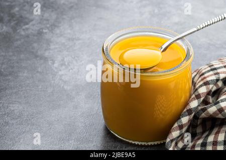 Purée de fruits jaune et orange dans un pot en verre sur fond gris Banque D'Images