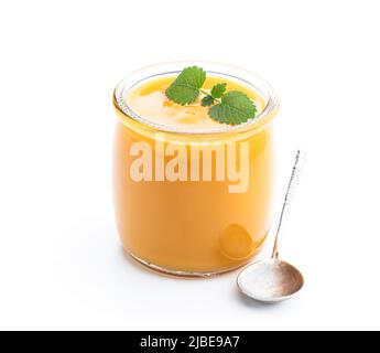 Purée de fruits jaune et orange dans un pot en verre isolé sur du blanc Banque D'Images