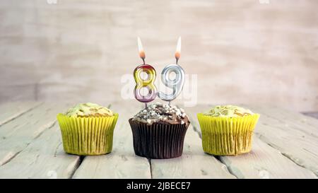 Joyeux anniversaire muffins avec des bougies avec le numéro. Espace de copie de carte avec chaussons pour Félicitations. Banque D'Images