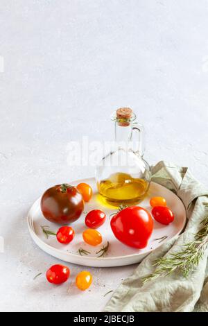 Plateau rond avec différentes variétés de tomates, sel et huile d'olive Banque D'Images