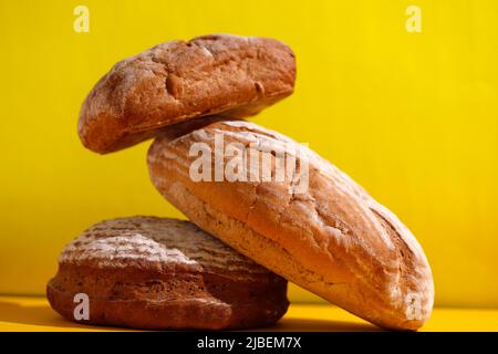 Sélection de pain rustique de Sourdough empilé cuit frais Focus sur table jaune, concept de style rétro Banque D'Images