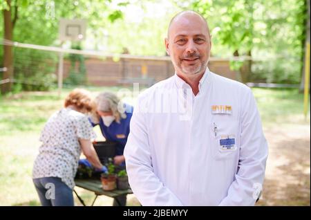 Berlin, Allemagne. 10th mai 2022. Torsten Kratz, spécialiste en neurologie, psychiatrie et gérontologie, explique comment la thérapie de jardin peut aider dans la « salle de traitement verte » de l'hôpital protestant Queen Elisabeth Herzberge. En arrière-plan, le Garden thérapeute travaille avec un patient. (À dpa 'la cueillette, le désherbage, la plantation: la thérapie de jardin sans médicament') Credit: Annette Riedl/dpa/Alay Live News Banque D'Images