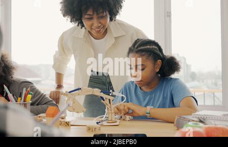 Salle de classe avec divers apprenants de heureusement des étudiants afro-américains et des enseignants faisant des activités ensemble. L'enseignant enseigne, guide et talki Banque D'Images