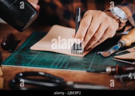 L'homme travaillant avec du cuir véritable dans l'atelier. Banque D'Images