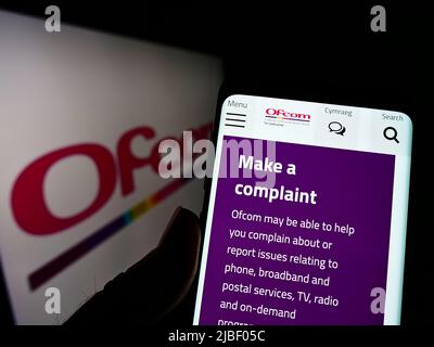 Personne tenant un téléphone portable avec le site Web de l'autorité britannique Office of Communications (Ofcom) à l'écran avec le logo. Concentrez-vous sur le centre de l'écran du téléphone. Banque D'Images