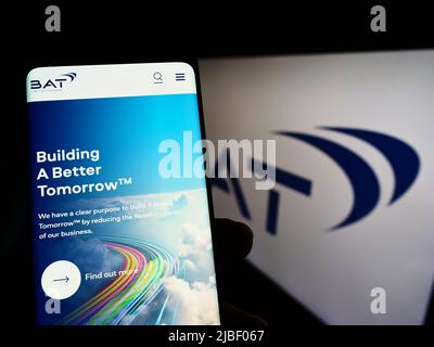 Personne tenant un téléphone portable avec le site Web de la société British American Tobacco plc (BAT) à l'écran devant le logo. Concentrez-vous sur le centre de l'écran du téléphone. Banque D'Images