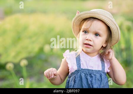 Portrait de l'enfant fille mangeant la gousse de pois à l'extérieur. Fille récolte des petits pois dans le jardin d'été. Helthy mangeant pour enfant. Jardinage, jardinier, petit enfant fermier belle fille avec légumes cueillis Banque D'Images