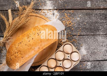 Pain rural frais avec des épillets de blé sur fond de bois Banque D'Images