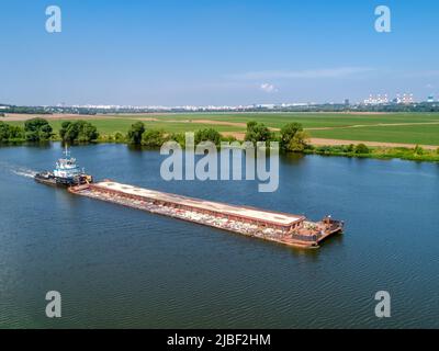 Towboat transporte la barge avec le sable le long de la rivière tranquille Banque D'Images