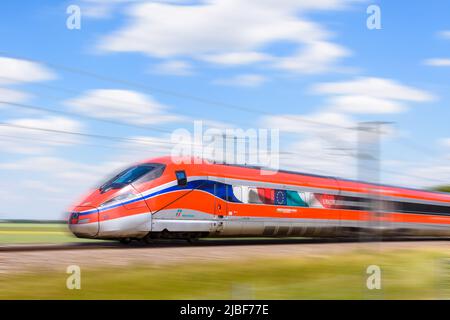 Un train à grande vitesse Frecciarossa (ETR 1000) de la compagnie ferroviaire italienne Trenitalia roule à pleine vitesse dans la campagne. Banque D'Images