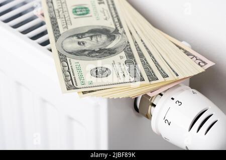 Pile de billets en dollars sur la batterie du radiateur de chauffage avec thermostat. Concept de coûts de chauffage coûteux et de croissance energ Banque D'Images