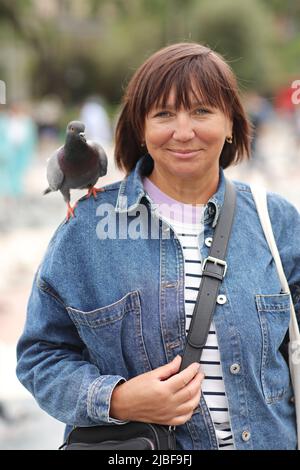 Femme souriante avec un pigeon sur son épaule. ravel autour de l'Europe. Banque D'Images