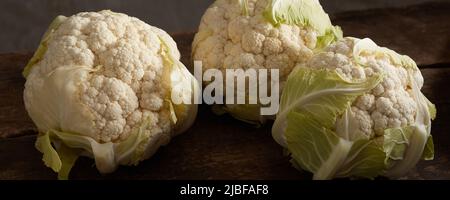 De dessus de tout le chou-fleur mûr placé sur une table en bois dans la cuisine rustique Banque D'Images