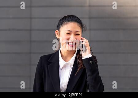 femme asiatique souriante parlant au téléphone Banque D'Images