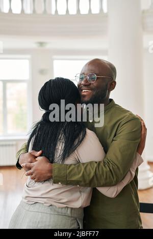 Jeune homme noir souriant donnant un câlin à une femme afro-américaine inquiète ou malheureuse tout en la réconfortant pendant la session psychologique Banque D'Images