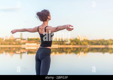 femme profitant du coucher du soleil avec les bras écartent et le visage élevé dans le ciel. Banque D'Images