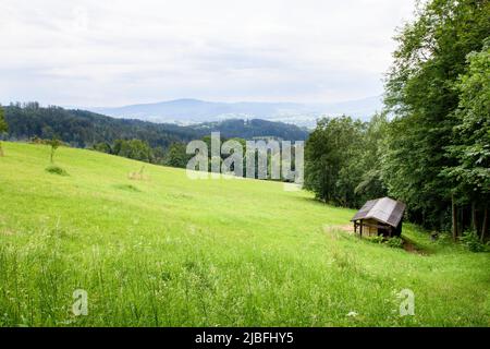 Vue sur le col de Jablunkov depuis les montagnes Loučka et Filipka. Cabane en bois sur un pré au premier plan. Silésie, République tchèque Banque D'Images