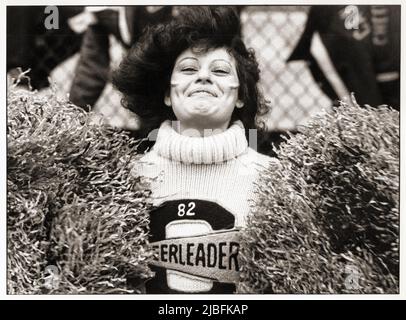 Une meneuse de la Canarsie High School fait des vagues sur ses pompons lors d'un match de 1982 au Midwood Field à Brooklyn, New York. Banque D'Images